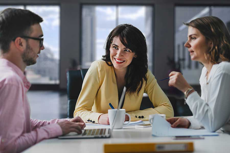 AdobeStock_209914233 Three people having meeting at a table discussing project