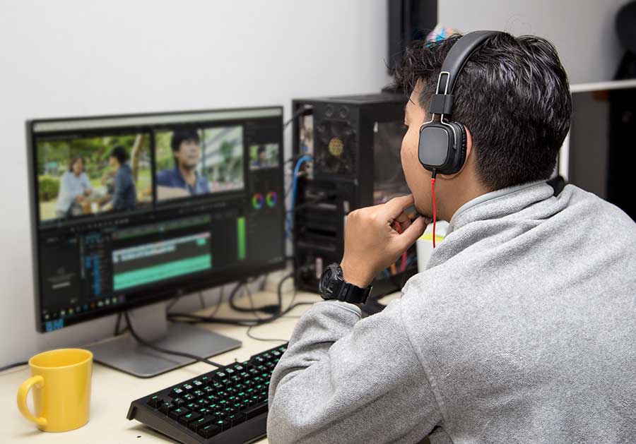 AdobeStock_294406796 Homme travaillant sur ordinateur avec un logiciel de montage vidéo