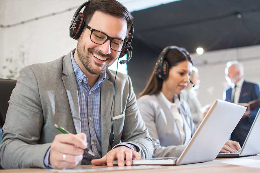 Man on office transcribing an audio file with headphones on