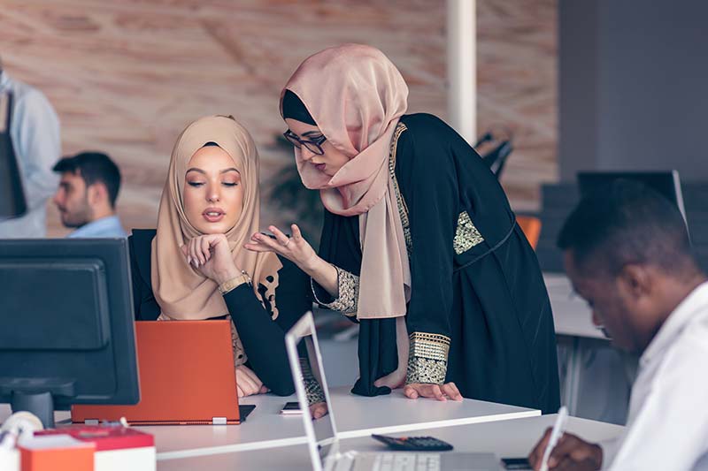 Two Arabic women talking at a desk