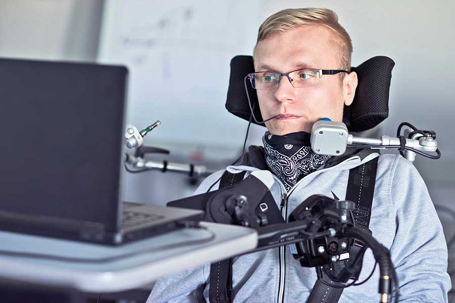 Homme handicapé en fauteuil roulant regardant son écran de navigation d’ordinateur. 