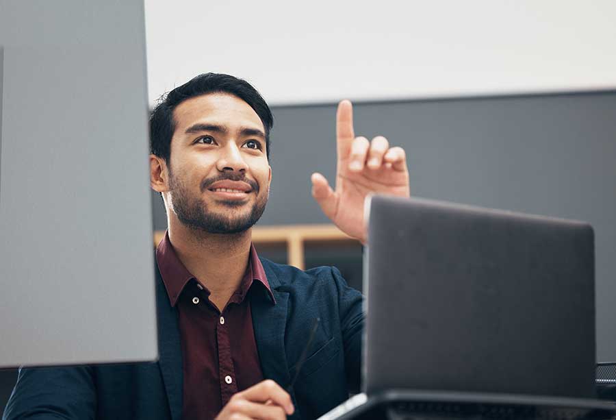 Translation-and-interpreting-buyers Man at desk with computer screens pointing.