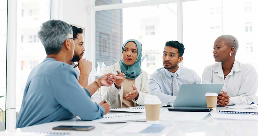 Translation-purchasing-managers Five people at a desk conversing.